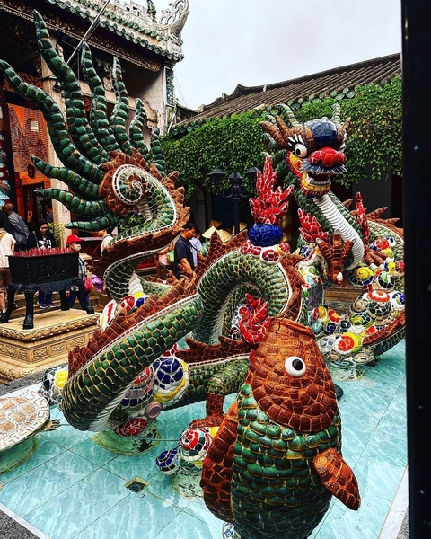       Vibrant mosaic dragon statue in a temple courtyard.
  