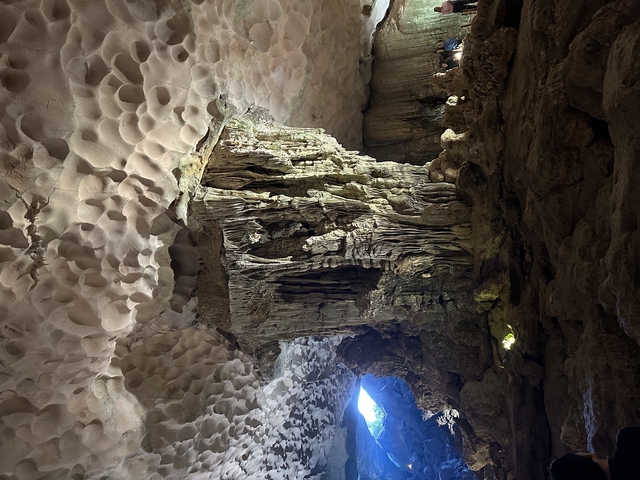 Interior of a limestone cave with formations and light filtering in.
