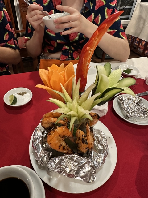      A decorative food display featuring carved fruit and grilled prawns.
  