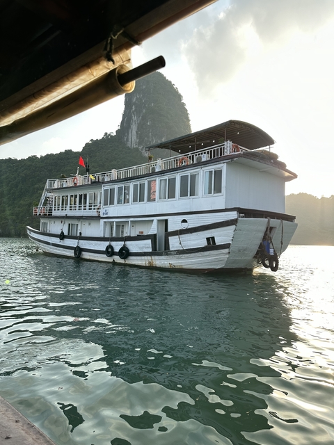 A wooden boat on the water with a backdrop of forested cliffs.