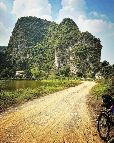       Dirt road along a river with a cliff in the background.
  