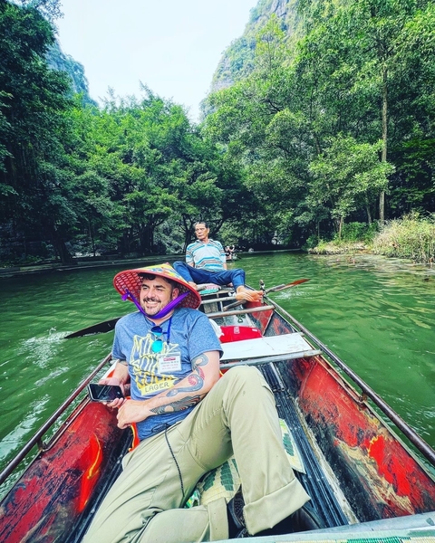       People rowing a boat in a river surrounded by nature.
  