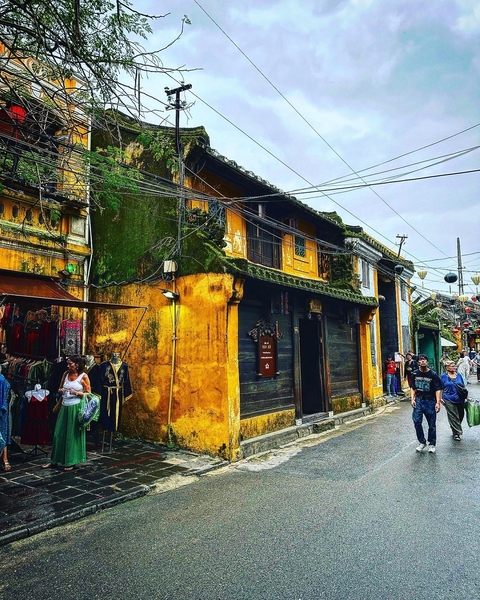       A vibrant street scene in Hoi An, Vietnam, with historic yellow buildings and people walking.
  