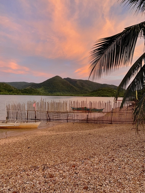 Serene sunset over a coastal area with mountains in the background.