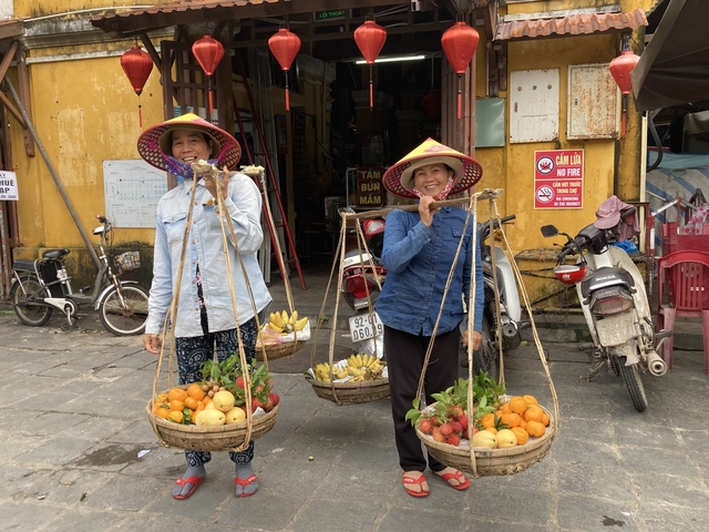 Women balancing baskets of fruits and vegetables.