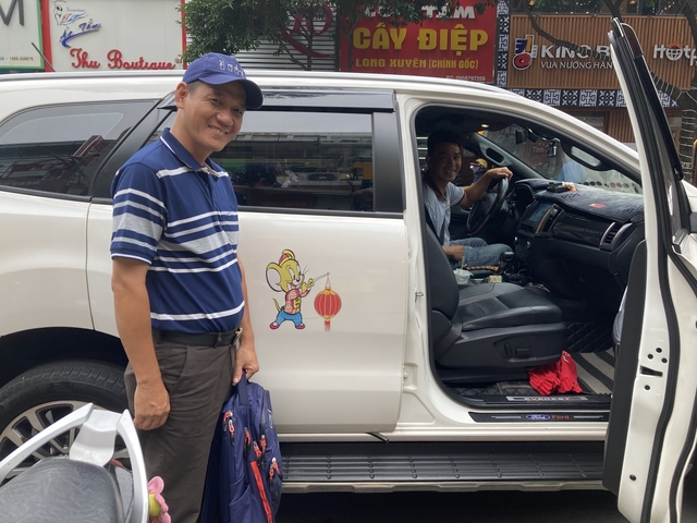       Two men standing by a vehicle with a cartoon decal.
  