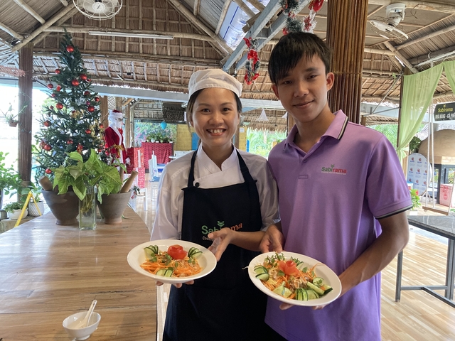       Two people posing with plates of food.
  
