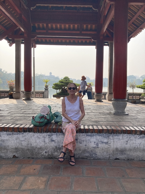      A woman sitting in front of a scenic view with stone pillars.
  