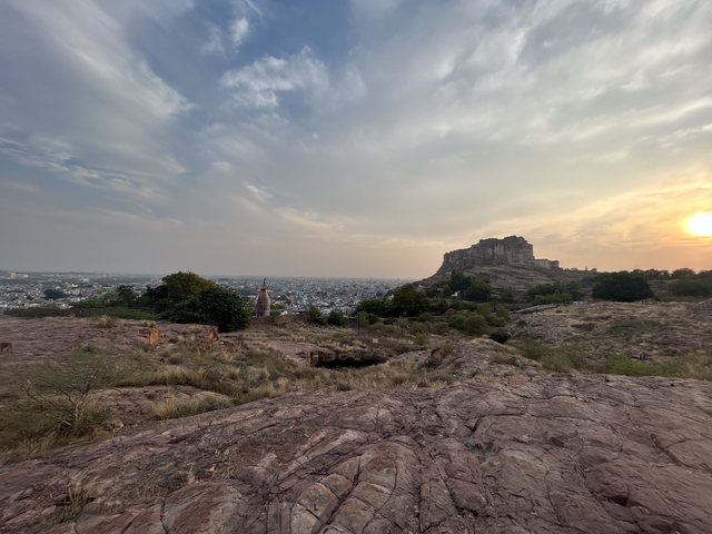       Distant view of a fort with a vast cityscape at sunset.
  