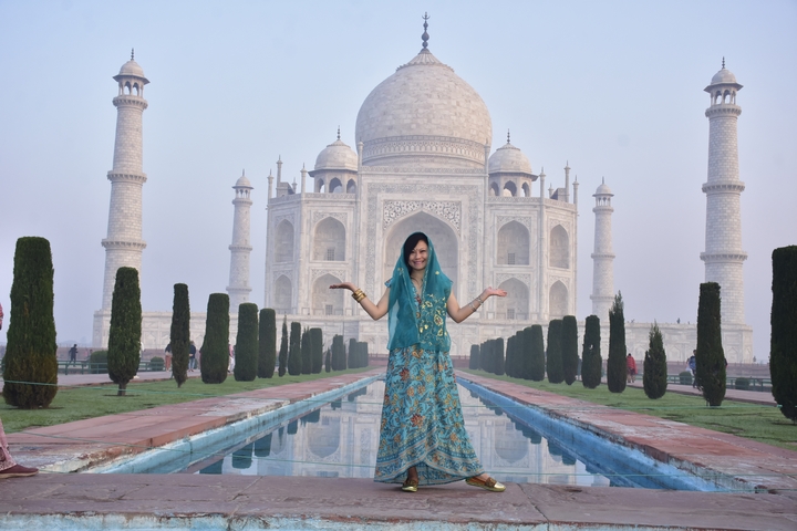       Woman in traditional attire in front of the Taj Mahal.
  