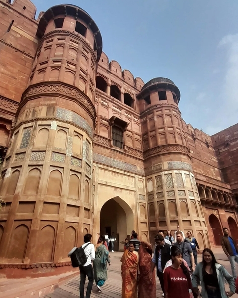 View of large fort walls made of red stone with intricate designs.