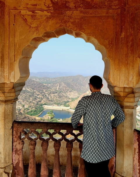 Person viewing a mountainous landscape from a decorated window.