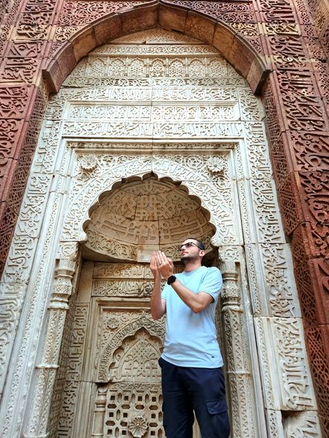 Person posing below an ornately carved stone archway.