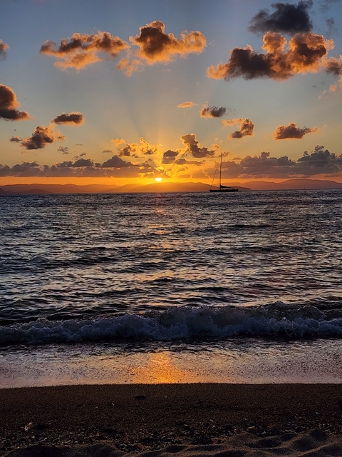       Silhouette of a sailboat against a colorful sunset sky.
  