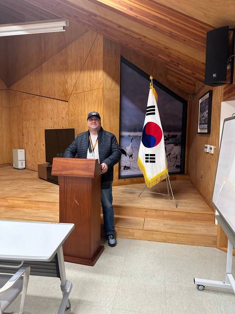       A person standing at a podium with a South Korean flag in the background.
  
