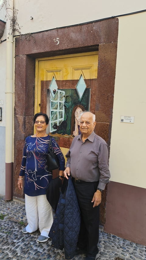       Two people standing in front of a painted wall.
  