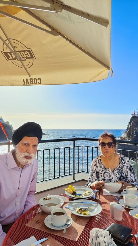       Two people seated on a balcony with an ocean view.
  