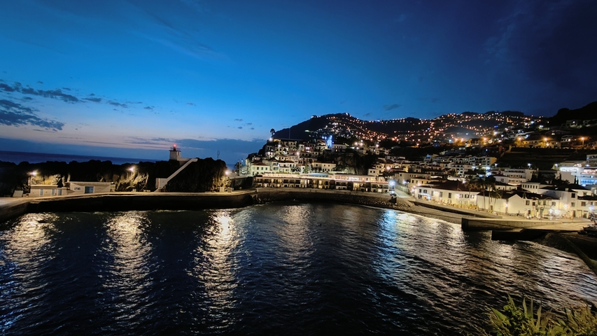       Nighttime coastal town with lights reflecting in the water.
  