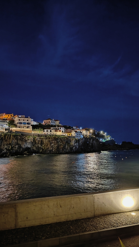       Picturesque coastal village with illuminated buildings at night.
  