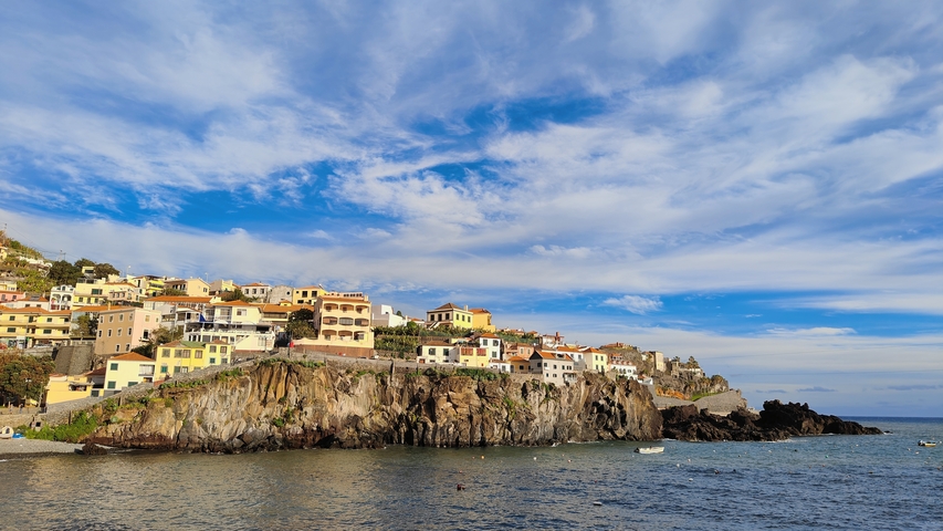       Coastal cliffside village with colorful houses and blue sky.
  