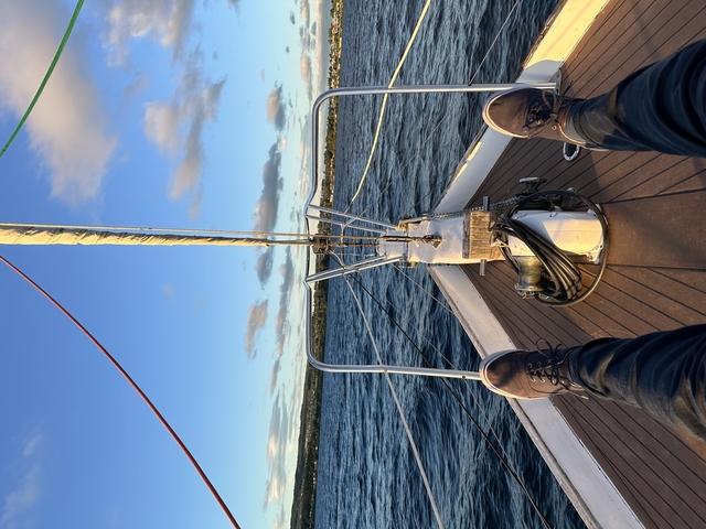       View from a boat showing legs and a coastal view.
  
