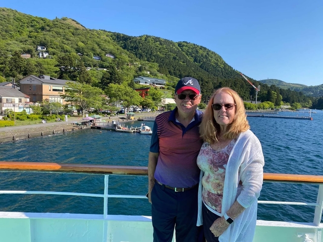 Couple on a boat with a scenic mountain and lake view.