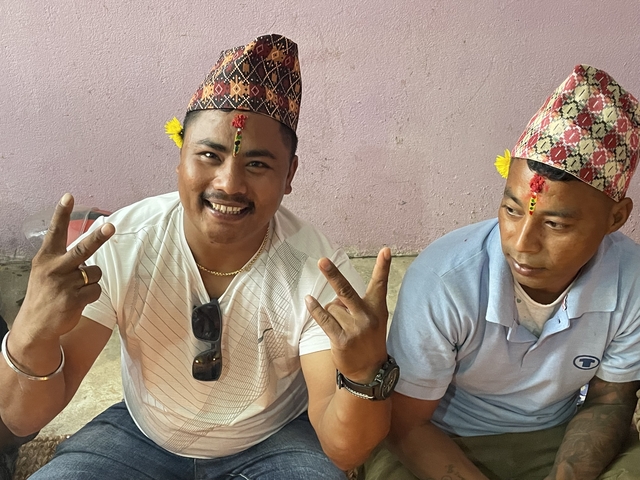       Two men with traditional hats and festive decorations.
  