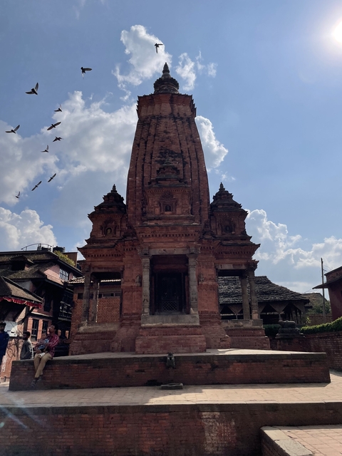       Ancient temple with birds flying over.
  