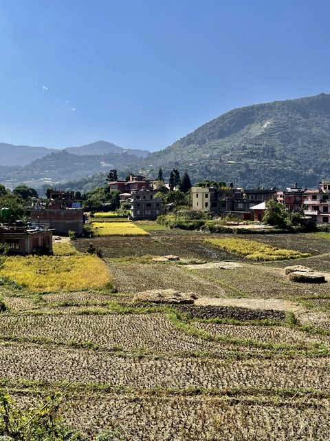       Scenic view of a rural landscape with mountains and houses.
  