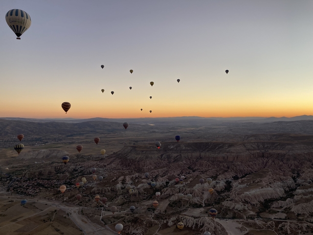 Hot air balloons floating over Cappadocia at sunrise.
