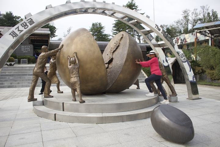 Tourist posing with sculptures of a divided sphere.