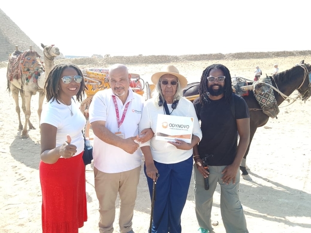 Group posing with camels in a desert setting.