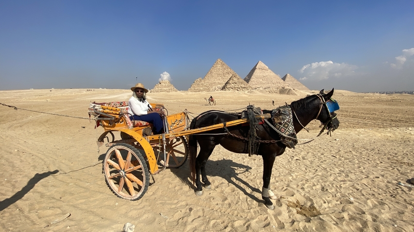 Woman posing with pyramids in the background.