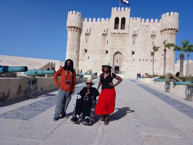 Group posing in front of a fortress with historical cannons.