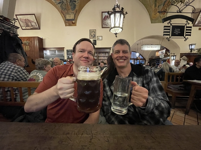 Two men enjoying large mugs of beer in a pub setting.
