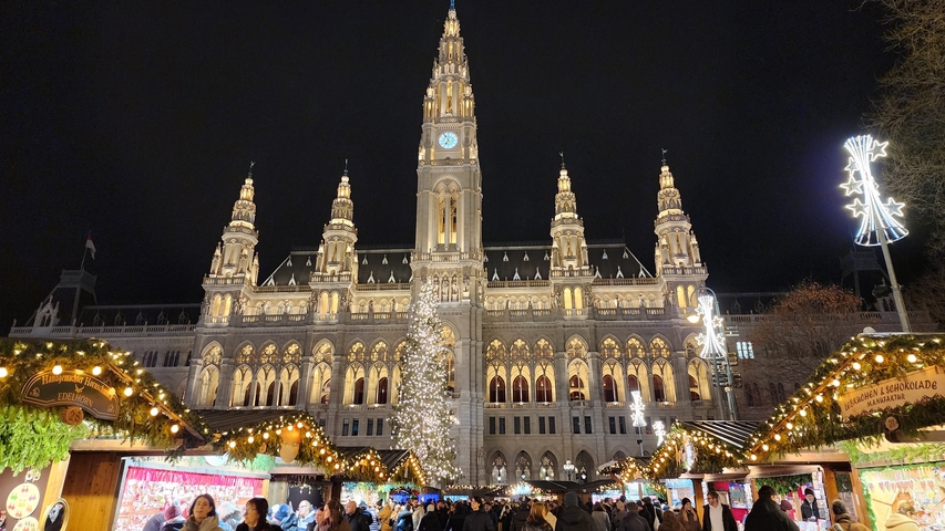 Rathaus decorated for Christmas market with illuminated stalls.