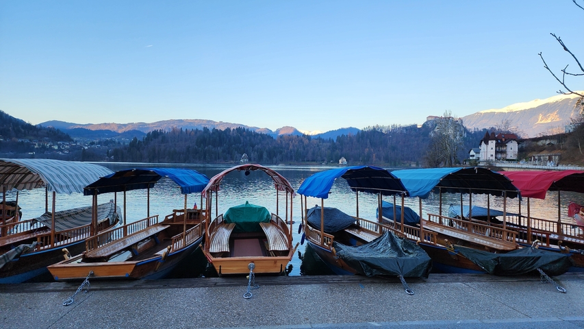 Boats docked at a serene lakeside with mountains in the background.