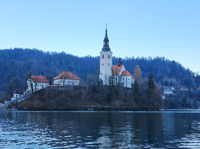 Church on an island surrounded by water and forested hills.