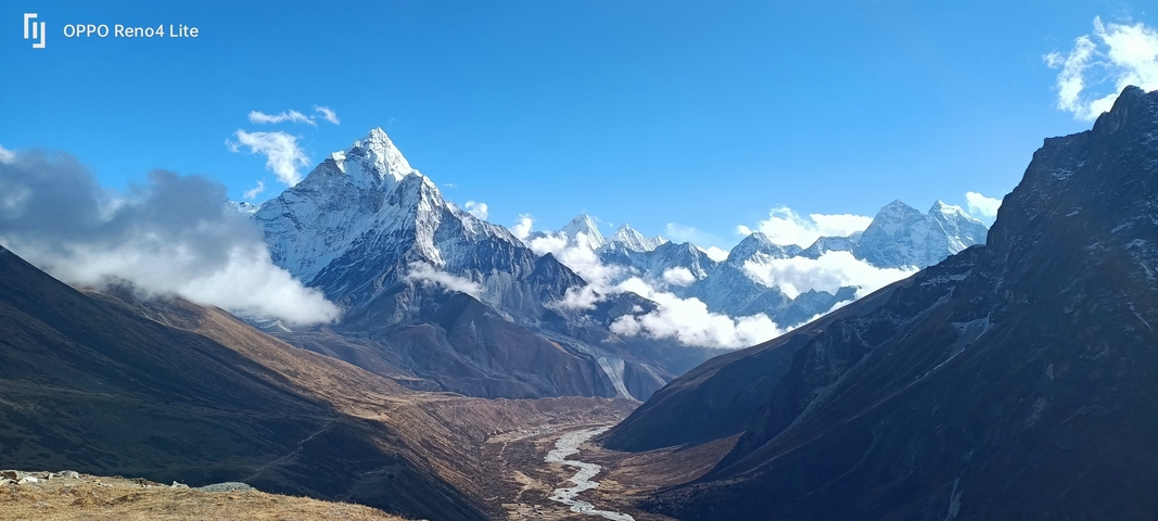       Mountain valley with a turquoise river and snowy peaks.
  
