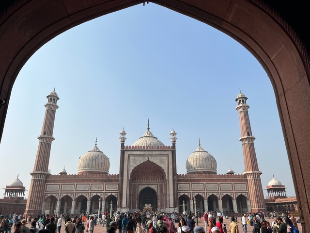       The façade of a mosque viewed through an ornate archway.
  