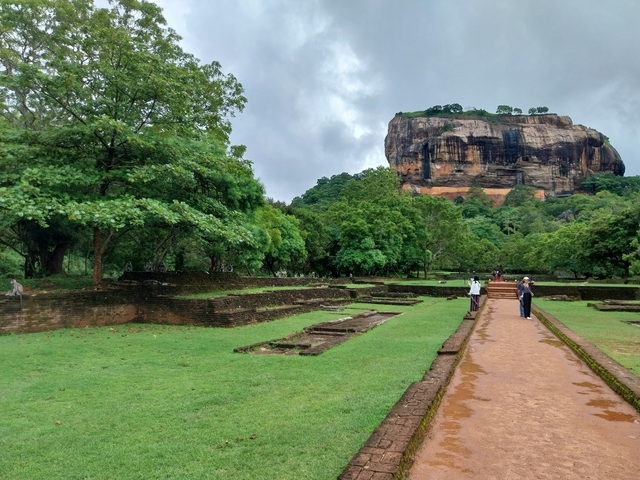 People walking on a path with Sigiriya Rock in the background.