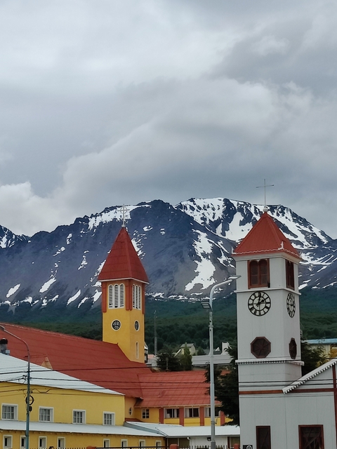       Snow-capped mountains with church towers in the foreground.
  