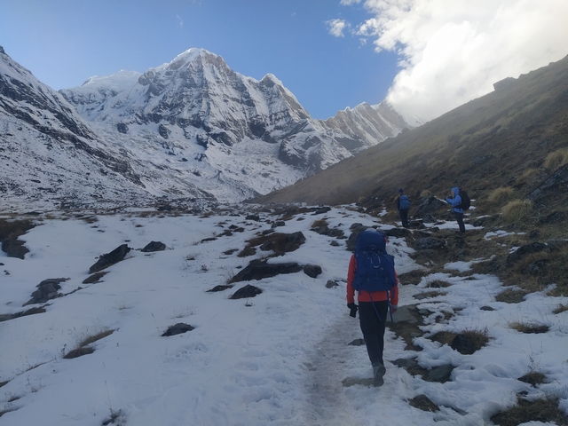       Hikers walking in a snowy mountain landscape.
  