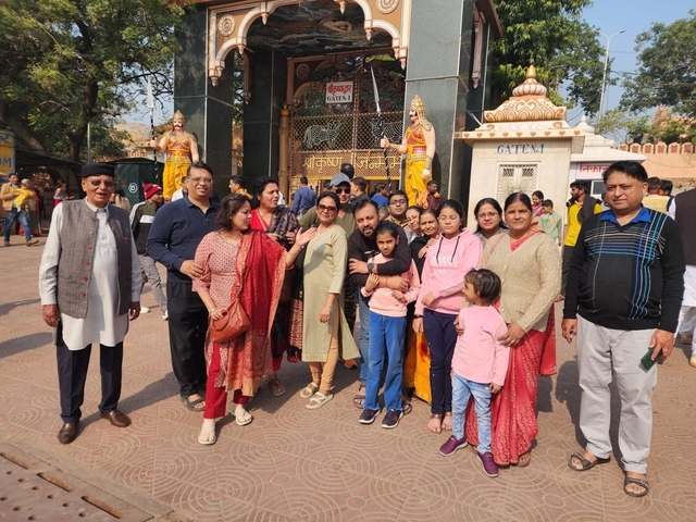       Large group of people posing in front of a gate.
  