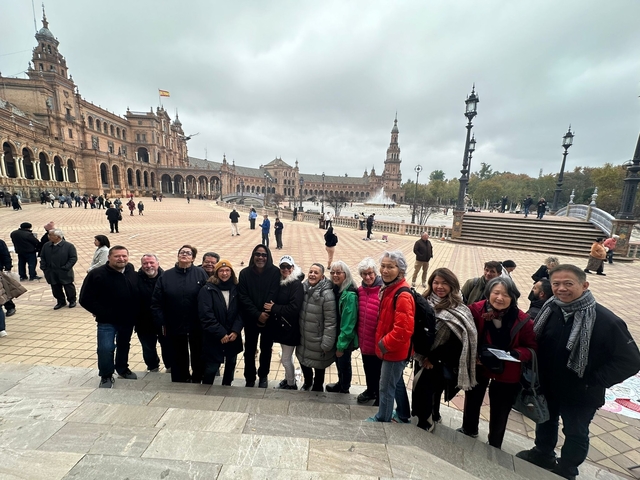       Group of people posing at Plaza de España with its iconic architecture.
  