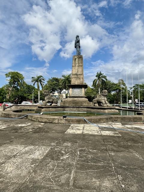       Stone monument with lion statues in a park.
  