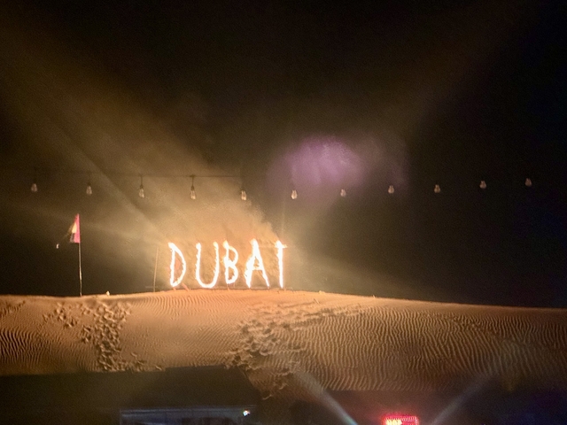       Illuminated desert landscape with a sign reading 'Dubai'.
  