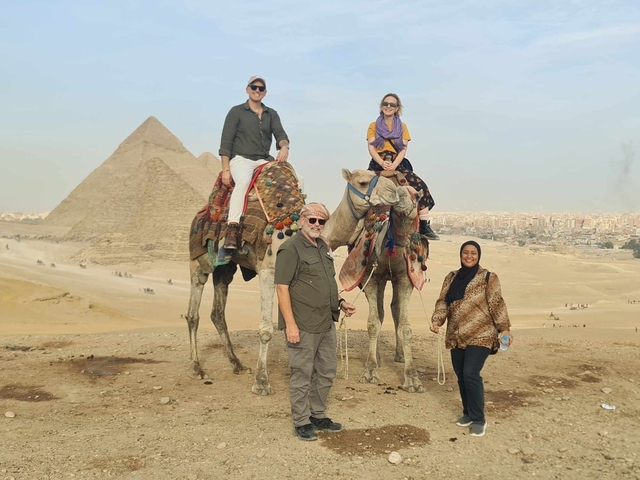 Group with camels in front of pyramids.