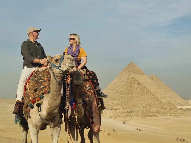 Tourists riding camels near the pyramids.