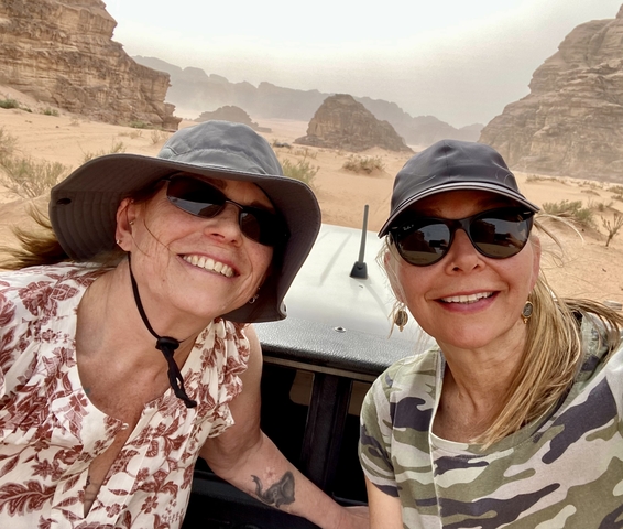 Two women smiling in a desert landscape.